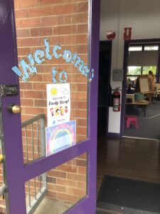 Open door with a Welcome to Kindy Group poster.