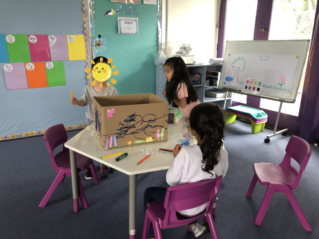 Kindy group participants observing a peer draw on a box.